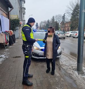 policjant wręcza kobiecie odblask