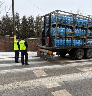 policjanci stoją przy aucie zaparkowanym w rejonie skrzyżowania