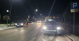 nocą policjanci stoją przy zatrzymanych pojazdach