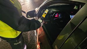 policjant trzyma urządzenie  do badania trzeźwości w ręku