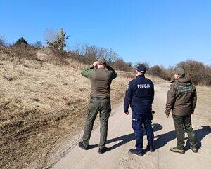 policjant ze strażą łowiecką obserwują teren