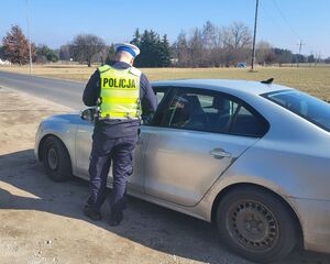 policjant stoi przy zatrzymanym pojeździe