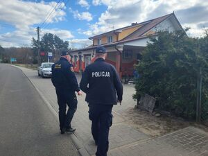 strażnik i policjant idą ulicą przy sklepie