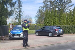 policjant stoi przy drodze i mierzy prędkośc