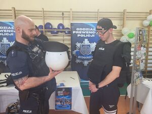policjant z oddziałów pomaga założyć policyjny sprzet