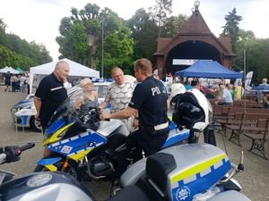 policjant stojący przy motocyklu z seniorami