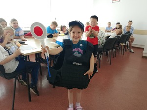 dziewczynka stoi trzymając w ręku lizak policyjny