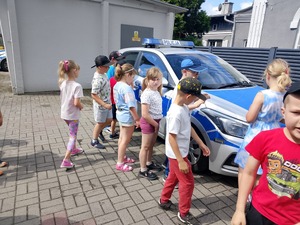 dzieci stoją przy radiowozie