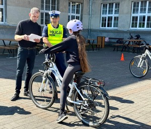 uczennica na rowerze stoi przy policjancie