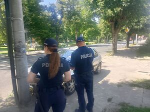 policjanci stoją przy pojeżdzie nieprawidłowo zaparkowanym