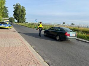 policjant podchodzi do zatrzymanego kierowcy pojazdu