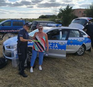 Policjantka wręczająca opaskę odblaskową kobiecie