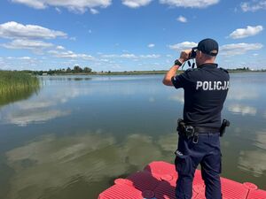 policjant obserwuje przez latarkę rzekę