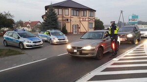 policjanci stoją przy autach na ulicy i badają trzeźwość
