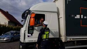 policjant stoi przy pojeździe ciężarowym i podaje alkomat kierowcy