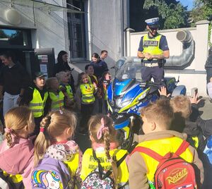 policjant stoi na motocyklu a wkoło niego dzieci