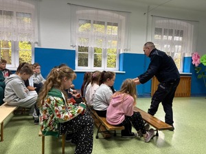 policjant wręcza ulotki dzieciom