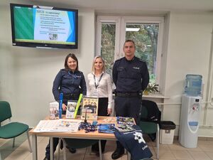 policjanci z pracownikiem stoją przy biurku